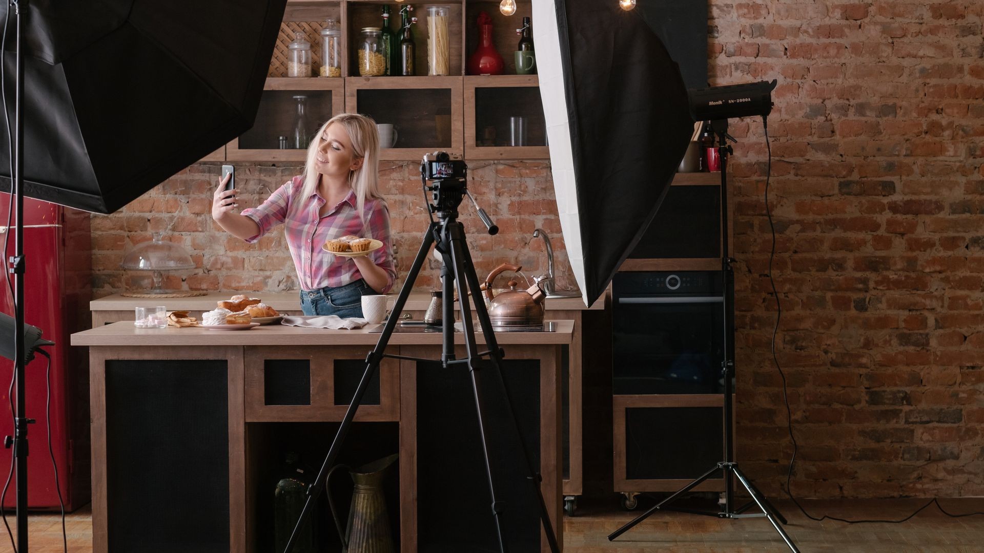 Homemade bakery. Cooking blog. Backstage photography. Smiling young woman with pastries taking selfie. Copy space.
